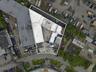 Aerial view of the parcel featuring a corner-lot orientation, paved exterior surface, and multiple attached industrial-style structures with flat roof