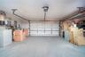Attached two-car garage featuring a sectional overhead door, automated door opener, finished concrete flooring, and an integrated electrical panel