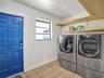 Utility space featuring tile flooring, a six-panel door, built-in wooden shelving, and a single-pane window