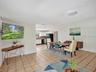 Open-concept interior featuring ceramic tile flooring, recessed lighting, and kitchen cabinetry with a neutral finish