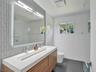 Floating vanity with a linear sink, wall-to-wall mirror, vertical-set subway tile backsplash, polished chrome hardware, and large-format floor tile