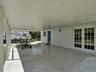 Covered carport featuring a smooth concrete floor, white support pillars, and glass-paned double doors