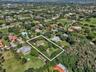 Aerial perspective of a property featuring a single-story residence, expansive lot, mature landscaping, and tree-lined perimeter