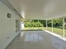 Screened-in patio featuring a solid roof, concrete flooring, exterior wall-mounted lighting, and double-door access