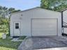 Detached metal workshop featuring a roll-up garage door, separate pedestrian entry, and a concrete apron