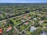Aerial perspective of a property featuring expansive grounds, mature canopy trees, a sprawling lawn, and a multi-pitched roofline