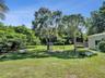 Expansive backyard featuring a large grass lawn, mature trees, and horizontal siding exterior