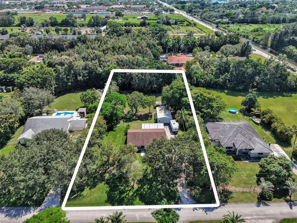 Expansive lot featuring mature trees, a detached storage structure, and a paved driveway