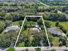 Expansive lot featuring mature trees, a detached storage structure, and a paved driveway