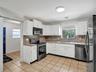 Kitchen featuring white cabinetry, stone-finish countertops, tiled flooring, and stainless steel appliances