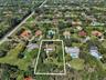 Aerial perspective of a multi-acre property featuring mature tree canopy, extensive open lawn space, and a paved driveway