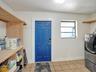 Utility area featuring natural wood-finish open shelving, paneled door with hardware, square ceramic floor tile, and a multi-pane window