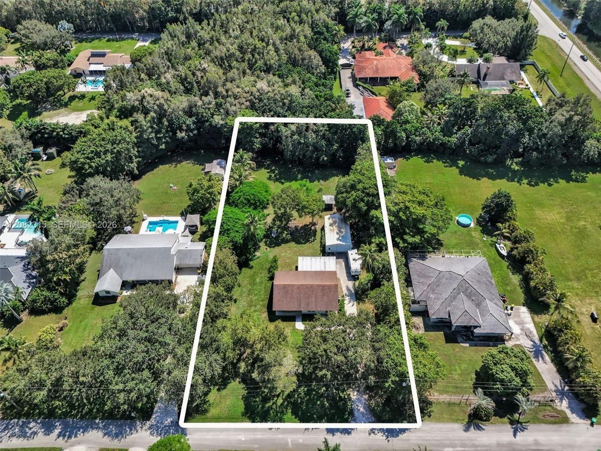 Expansive rectangular lot featuring established mature trees, sprawling green space, and a paved driveway