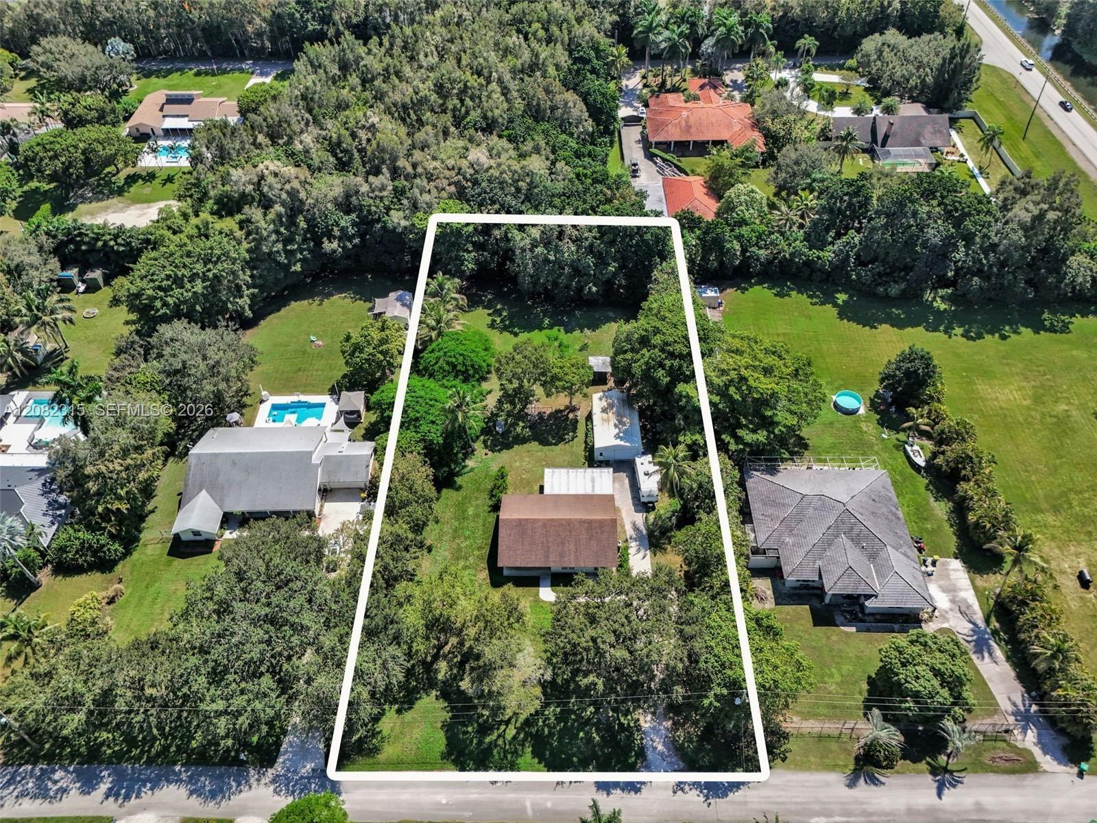 Expansive rectangular lot featuring established mature trees, sprawling green space, and a paved driveway