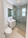 Neutral-toned ceramic tile flooring, dual-panel closet doors, ceiling fan with integrated lighting, and large windows providing natural illumination