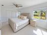 High-gloss white cabinetry, stainless steel French-door refrigerator, stone-surface countertop, recessed ceiling lighting, and large-format tile floor