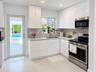 Contemporary interior featuring high-gloss white cabinetry, stainless steel refrigerator, large-format tile flooring, and recessed lighting