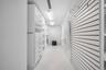 Walk-in closet featuring white built-in cabinetry with integrated drawers, slat-wall organizational system with adjustable hooks, tile flooring, and l