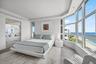 Floor-to-ceiling bay windows with oceanfront exposure, large-format tile flooring, recessed lighting, and mirrored wall panels