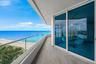 Covered terrace featuring wood-finish tile flooring, floor-to-ceiling glass sliding doors, and a glass panel railing overlooking the coastline