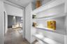 Built-in white floating shelving with integrated recessed lighting and wood-finish tile flooring