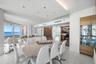 Open-concept living space featuring high-gloss tile flooring, recessed tray ceiling lighting, built-in wooden cabinetry with glass-front shelving, sli