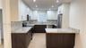 Kitchen featuring two-tone cabinetry, stone-finish countertops, stainless steel appliances, recessed ceiling lighting, and wood-finish flooring