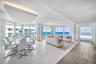 Open-concept interior featuring floor-to-ceiling glass windows, ocean scenery, white tile flooring, and a recessed ceiling architectural detail with i