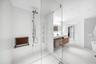 Walk-in shower with floor-to-ceiling tile, frameless glass enclosure, wall-mounted shower panel with handheld sprayer, built-in shelving, and integrat