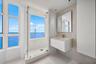 Glass-enclosed shower with integrated window, floating vanity, wall-mounted mirror, mosaic tile accent wall, and floor-to-ceiling windows with water b