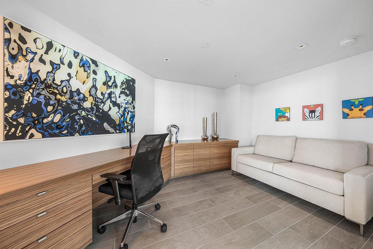 Custom wood-finish built-in cabinetry, integrated desk workspace, recessed lighting, and large-format tile flooring