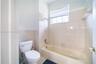 Bathroom featuring a porcelain tub with a shower head, tiled wall surround, and a multi-pane window with integrated blinds