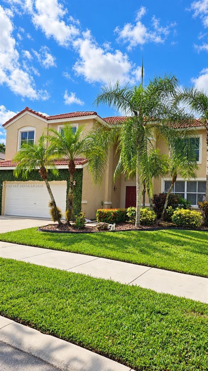 Two-story residence featuring a terracotta-tiled roof, stucco exterior, multi-pane windows, and a paved driveway leading to a two-car garage