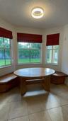 Bay window featuring built-in wooden bench seating, neutral floor tile, and a flush-mount overhead light fixture