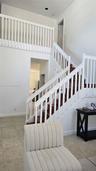 High-ceiling foyer featuring a staircase with wood-finish treads, white railings, and tile flooring
