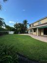 Expansive backyard featuring a manicured lawn, paver patio, attached retractable awning, and perimeter privacy fencing