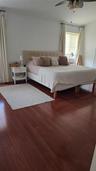 Bedroom featuring wood-finish flooring, a ceiling fan with integrated lighting, and window treatments