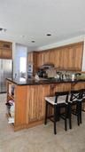 Kitchen featuring natural wood cabinetry, polished stone countertops, stainless steel wall-mounted oven, and built-in shelving integrated into the pen