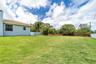 Expansive lawn featuring mature landscaping, a tile roof, and perimeter fencing