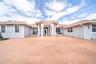 Single-story exterior featuring a clay tile roof, arched entryway with decorative columns, and expansive paved courtyard