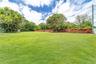 Expansive grass lawn featuring mature trees and a perimeter wood-slat fence