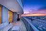Expansive covered balcony featuring tile flooring, glass panel railings, and floor-to-ceiling glass wall panels