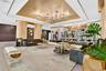 Metallic tray ceiling, large-scale multi-bulb crystal chandeliers, curved light-wood structural columns, integrated architectural shelving, and recess