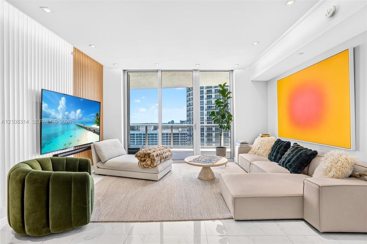 Living area featuring floor-to-ceiling glass windows, recessed lighting, white tile flooring, and a decorative wood-slat accent wall