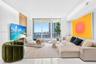 Living area featuring floor-to-ceiling glass windows, recessed lighting, white tile flooring, and a decorative wood-slat accent wall