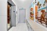 Elevator access featuring metallic sliding doors, white large-format stone-look floor tiles, and custom built-in cabinetry with a stone countertop