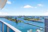 Elevated balcony featuring a glass panel railing and panoramic water-facing vistas of the coastline, islands, and metropolitan skyline