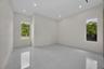 Neutral-toned interior room featuring large-format tile flooring, recessed ceiling lighting, and two windows providing natural illumination