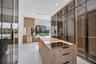 Custom built-in wood-finish cabinetry with full-height glass doors, integrated vertical LED accent lighting, central storage island with glass-top dis