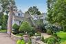 Multi-level exterior featuring light-toned  siding, a masonry chimney, stone retaining walls, structured landscaping, and a paved walkway